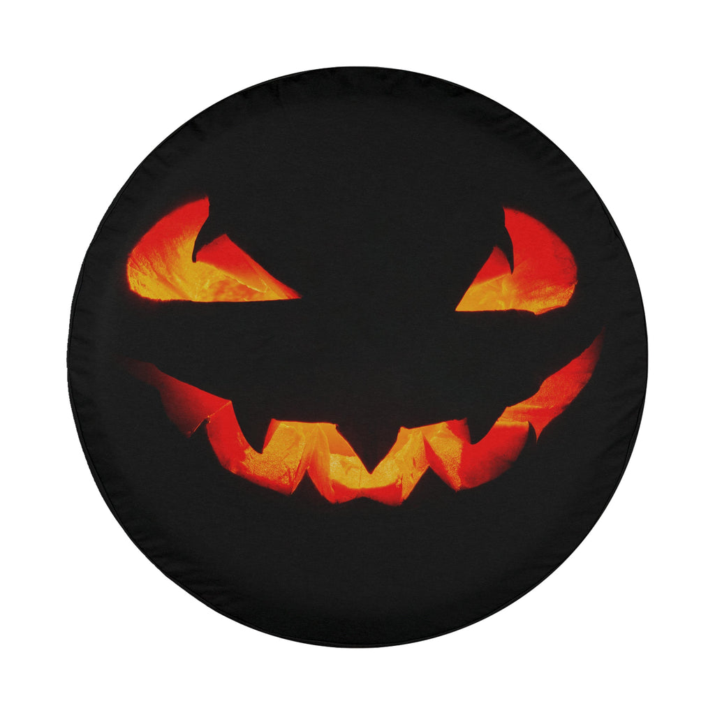 A Halloween-themed wheel cover with a jack-o-lantern design, featuring glowing orange and red eyes and sharp teeth.