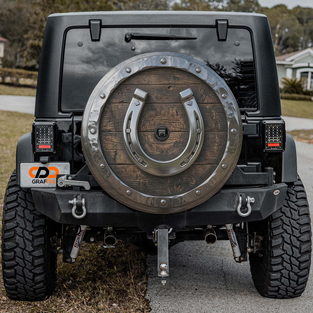 the rear of a black Jeep Wrangler with a large wooden shield-like decoration on the back.