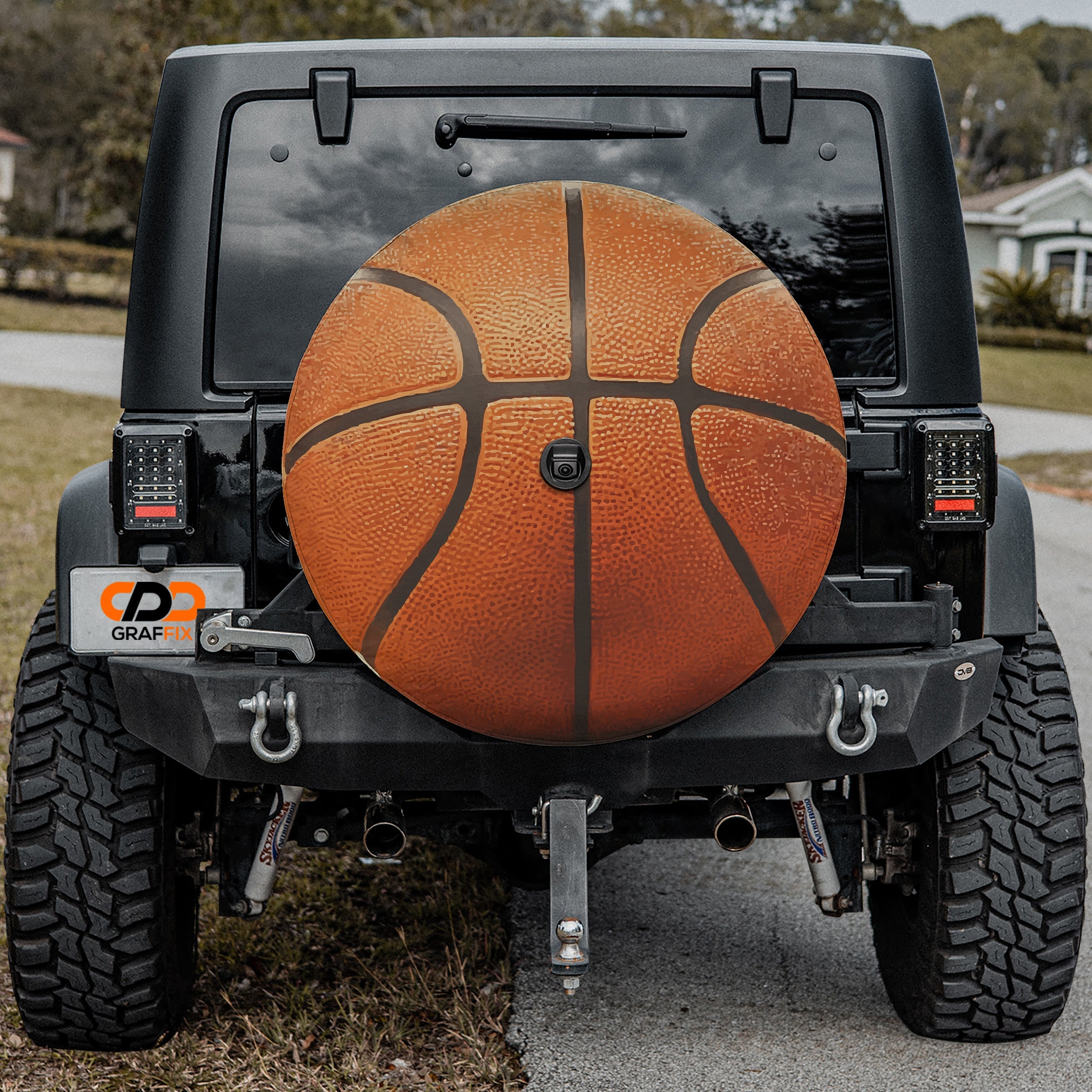 Basketball orange spare tire cover mounted on black Jeep Wrangler rear outdoors view