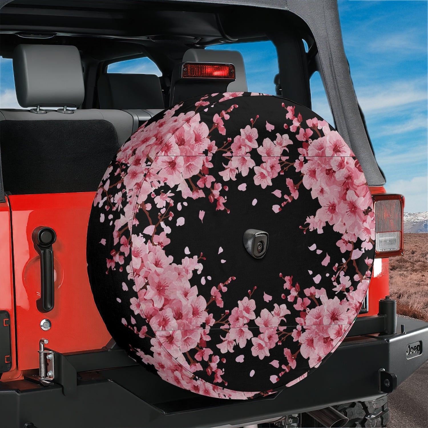 Japanese pink cherry blossom black background spare tire cover installed on red Jeep Wrangler rear