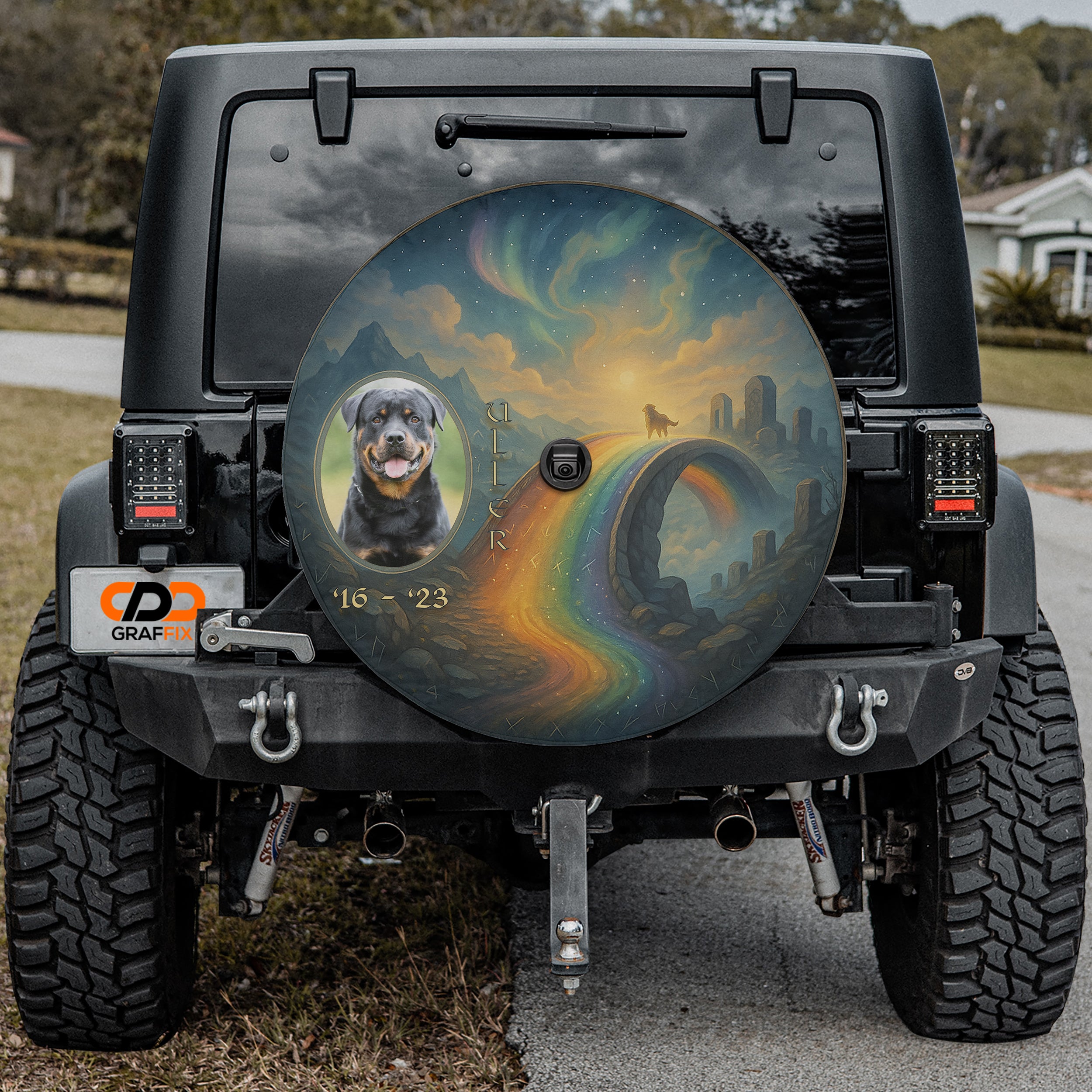 a black Jeep Wrangler with a large, colorful wheel cover depicting a rainbow and a dog.