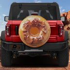 Glazed maple bacon donut spare tire cover on red Ford Bronco showing iced ring topped with chopped bacon bits
