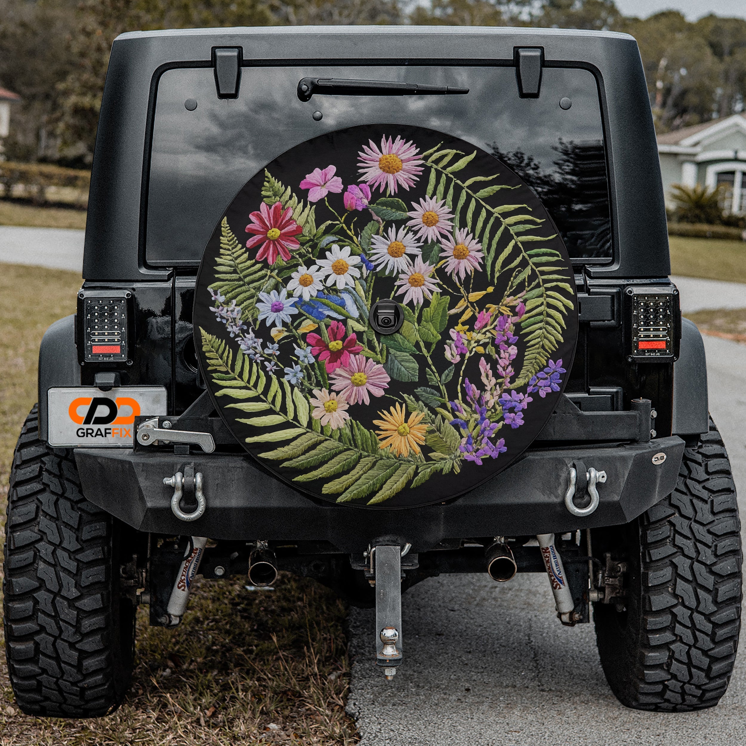 Faux embroidery wildflowers spare tire cover mounted angled view on red SUV outdoors