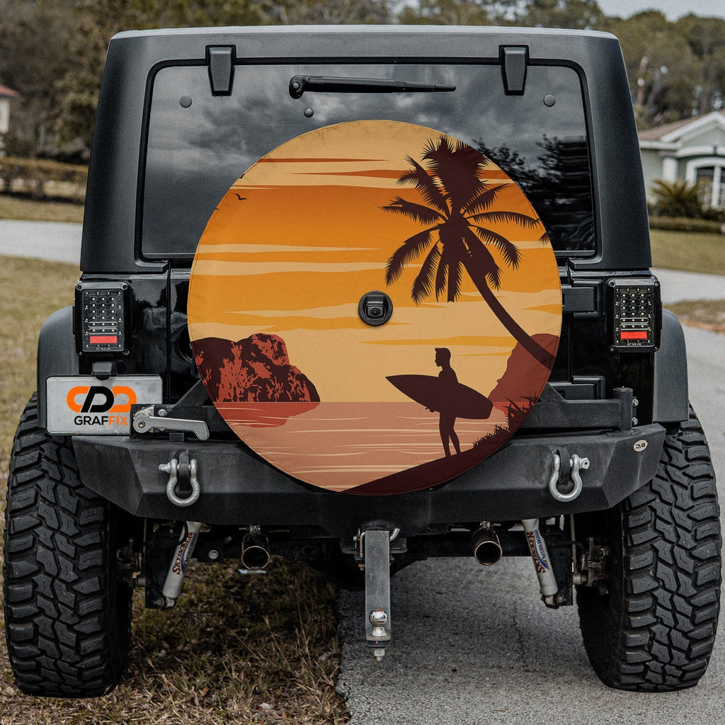 Sunset surfer tire cover on red Jeep Wrangler showing orange sky, palm tree, and lone surfer silhouette scene