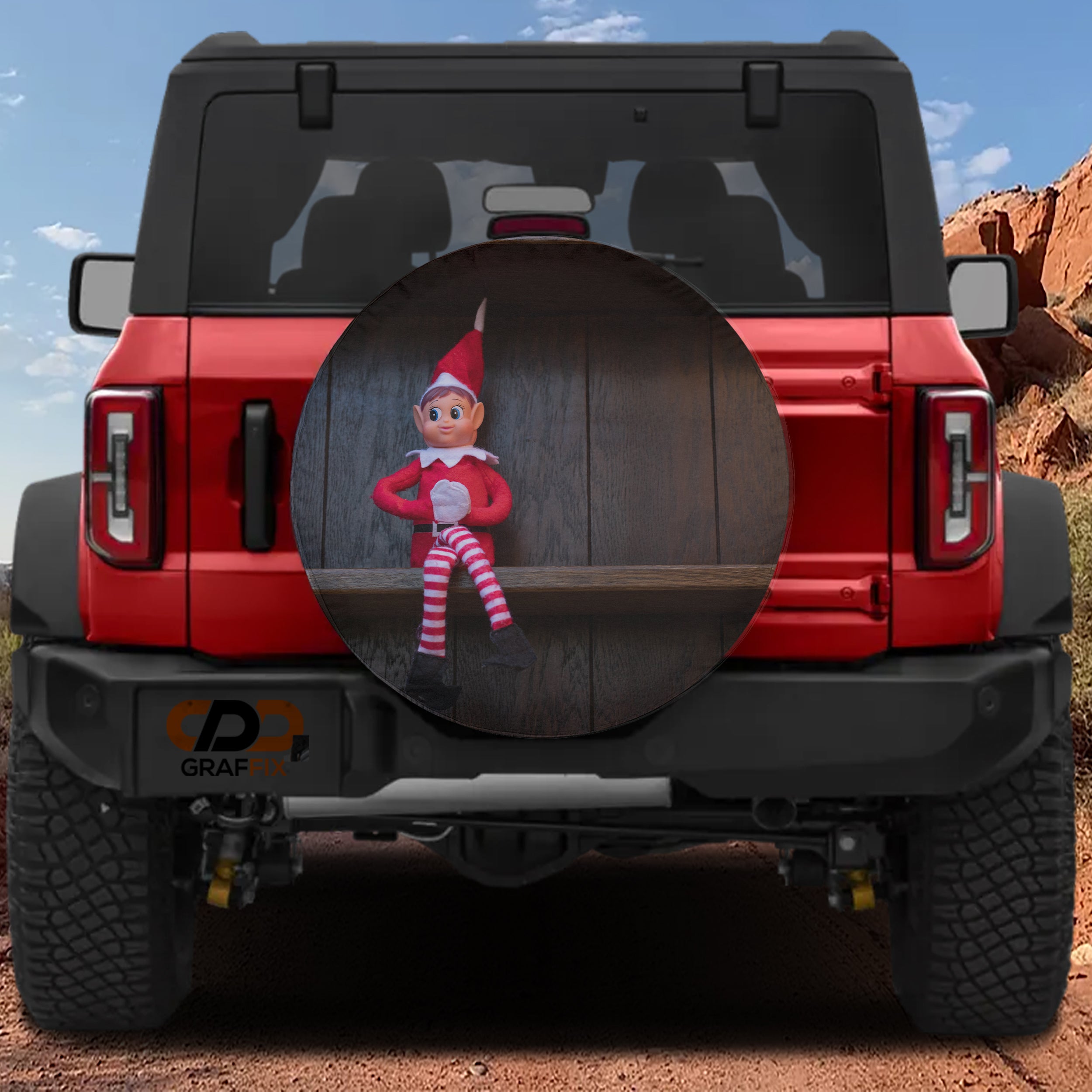 Shelfside Shenanigans spare tire cover on a red Jeep Wrangler showing the holiday elf perched on a circular cover