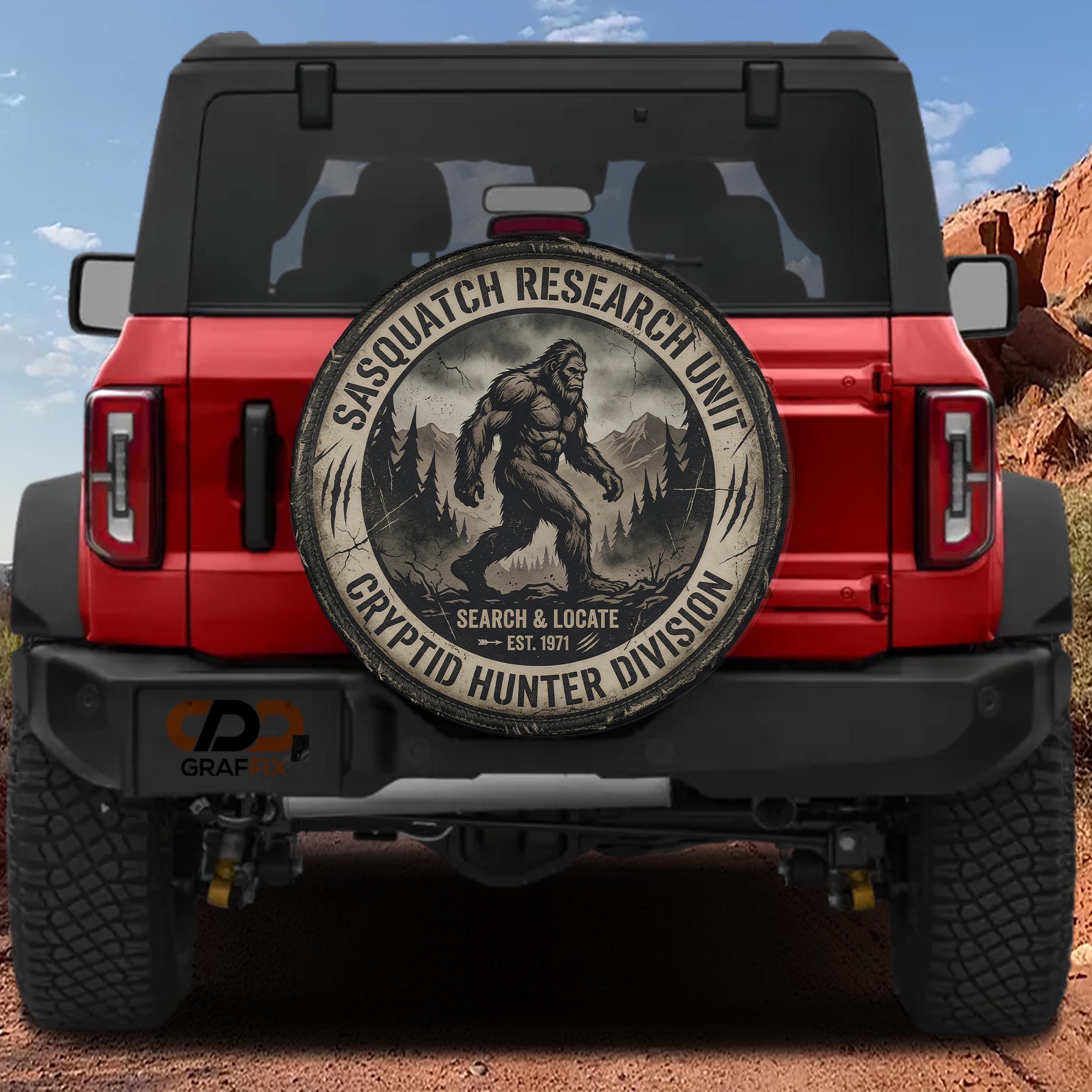 a red Jeep Wrangler with a large tire cover on the back, displaying a Sasquatch logo and text related to the Sasquatch Research Unit.