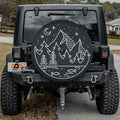 Midnight Pines spare tire cover with line-art pine forest scene mounted on Jeep Wrangler