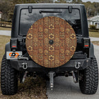 Tiki Wood carved totem and flower pattern tire cover installed on red Jeep Wrangler at rocky desert