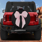 the rear of a red Jeep Wrangler with a large pink bow on the spare tire cover.