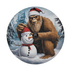Bigfoot Sasquatch with Santa hat building snowman round tire cover art and central camera cutout