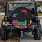 Pixel block puzzle tire cover on red Jeep Wrangler showing 8-bit gaming bricks with backup camera port