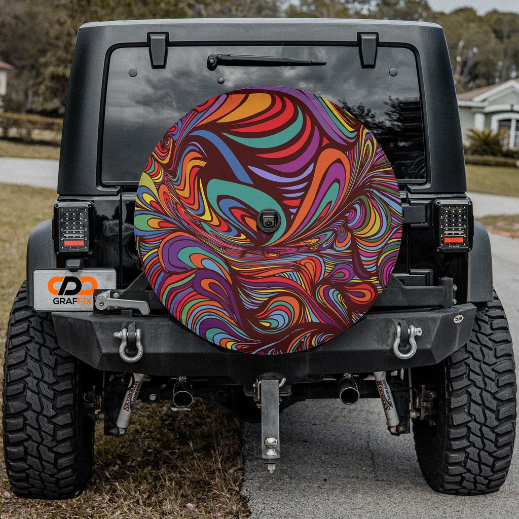 Psychedelic rainbow swirl tire cover on black Jeep Wrangler with neighborhood street and grass behind