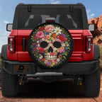 a red Jeep Wrangler with a large floral skull-shaped spare tire cover on the rear.
