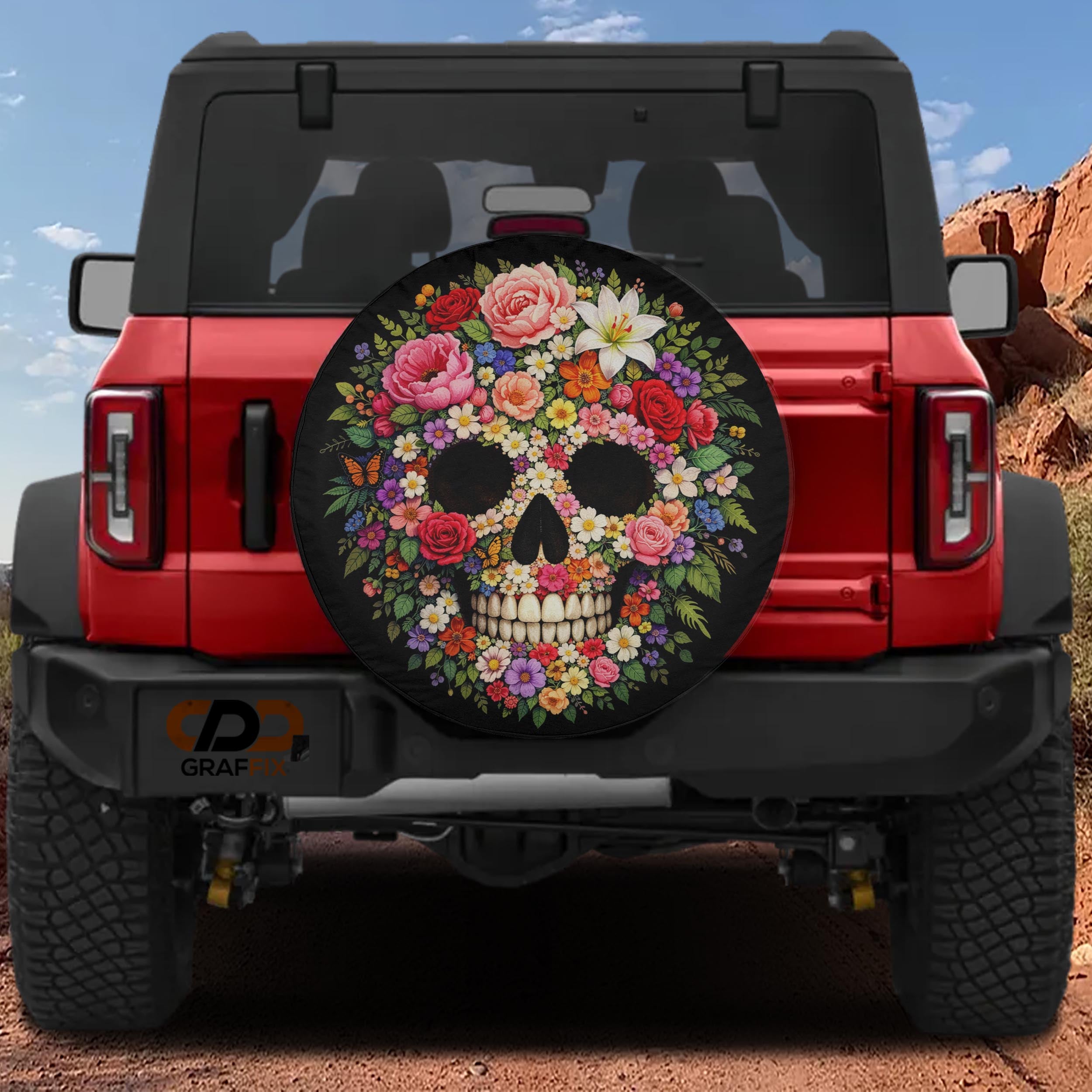 a red Jeep Wrangler with a large floral skull-shaped spare tire cover on the rear.