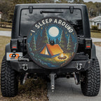 Flat round I sleep around camping edition tire cover closeup with orange tent campfire moonlit pine trees