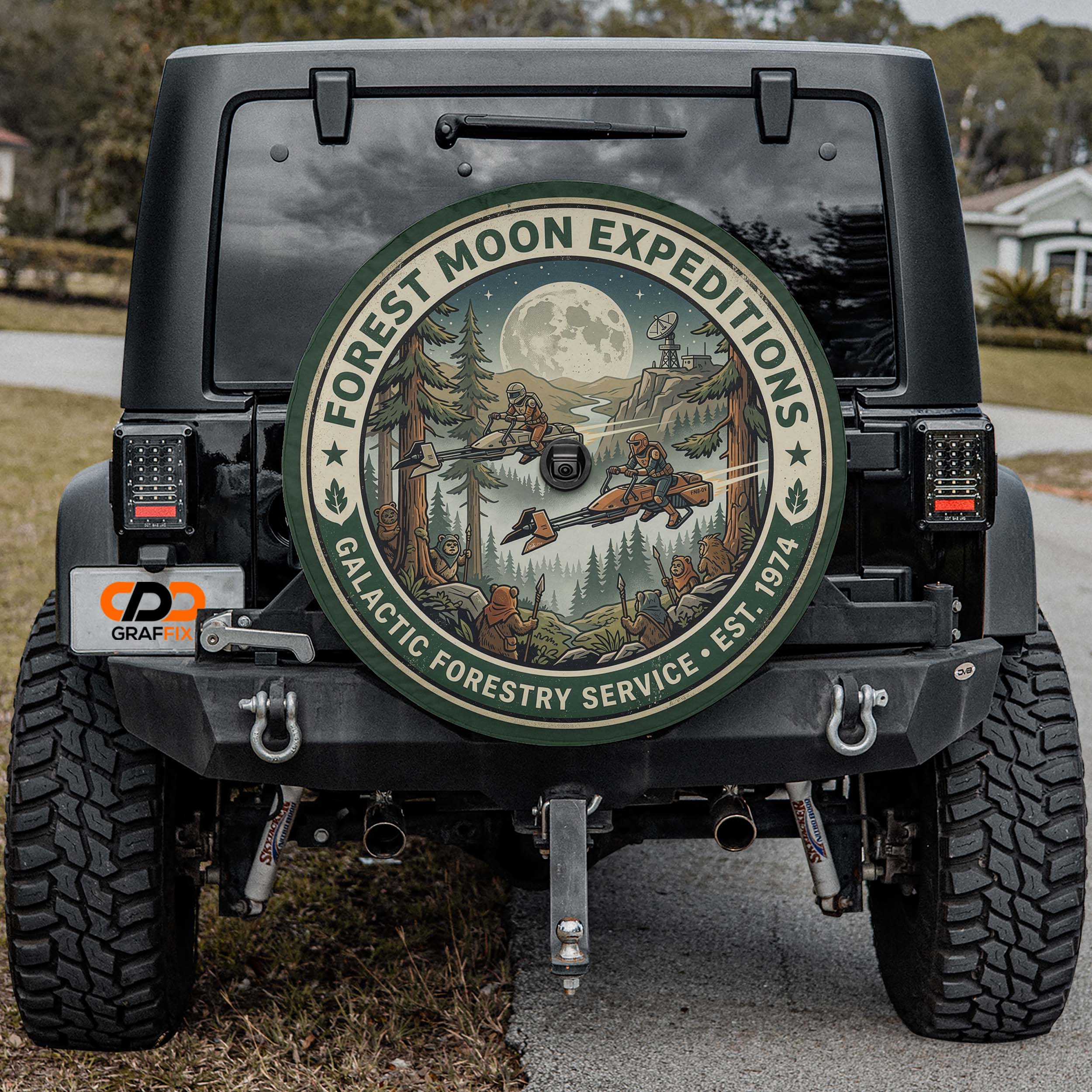 the back of a black Jeep Wrangler with a large circular decal on the rear window, featuring a forest scene with a full moon and stars.