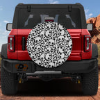 Skull and crossbones tire cover on red Ford Bronco with cartoon black-and-white skulls and bone pile pattern