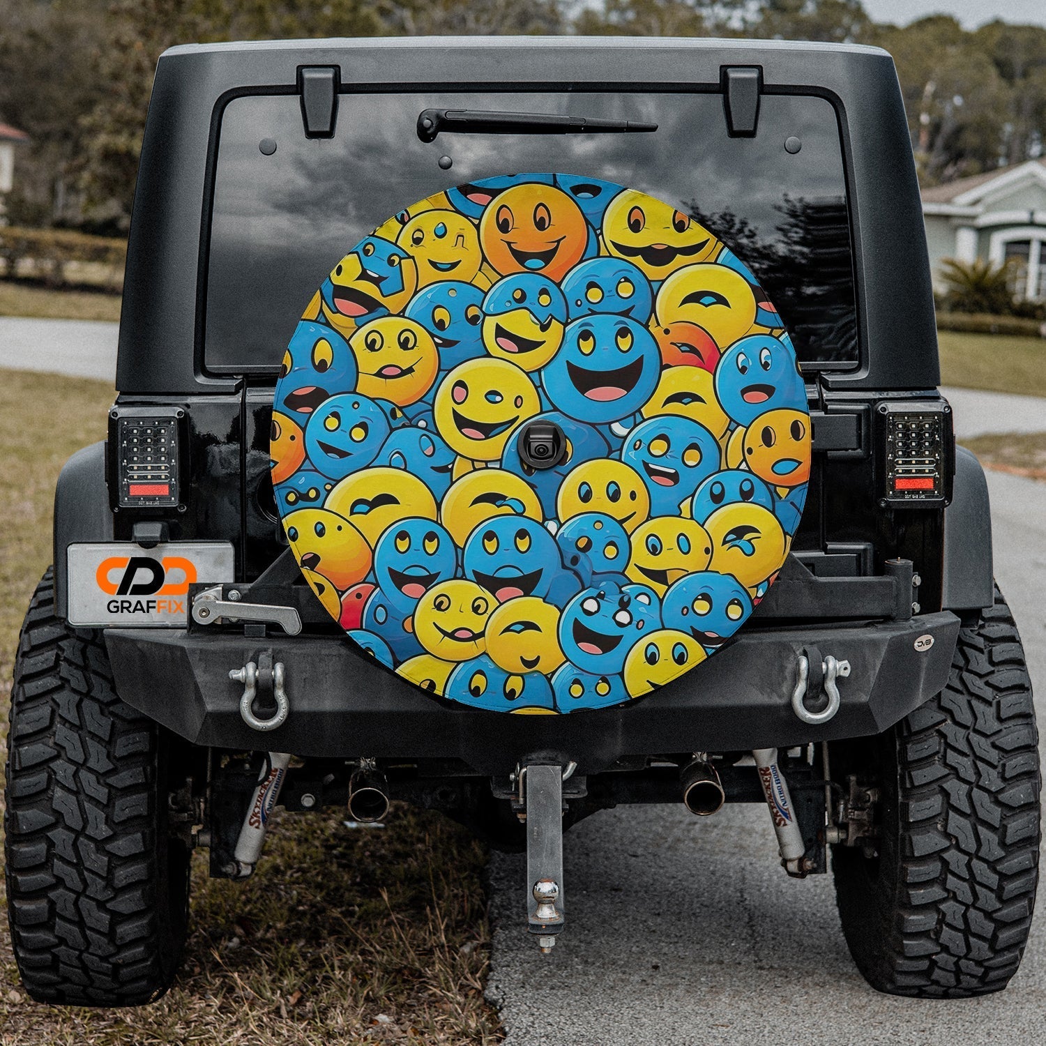 Happy smiley emoji faces tire cover on black Jeep Wrangler rear in suburban driveway with grass strip