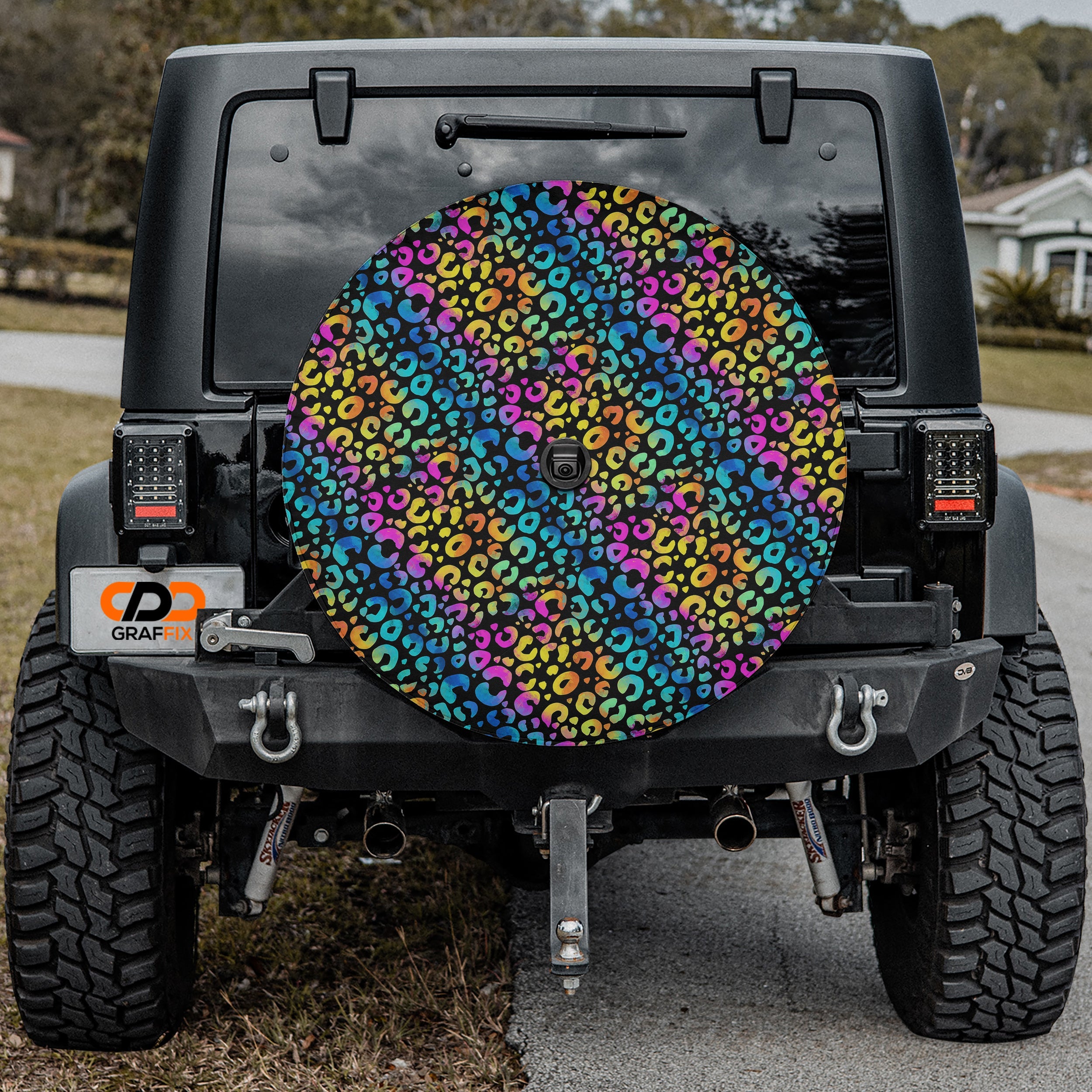 Leopard rainbow print spare tire cover mounted on red Ford Bronco rear in desert setting