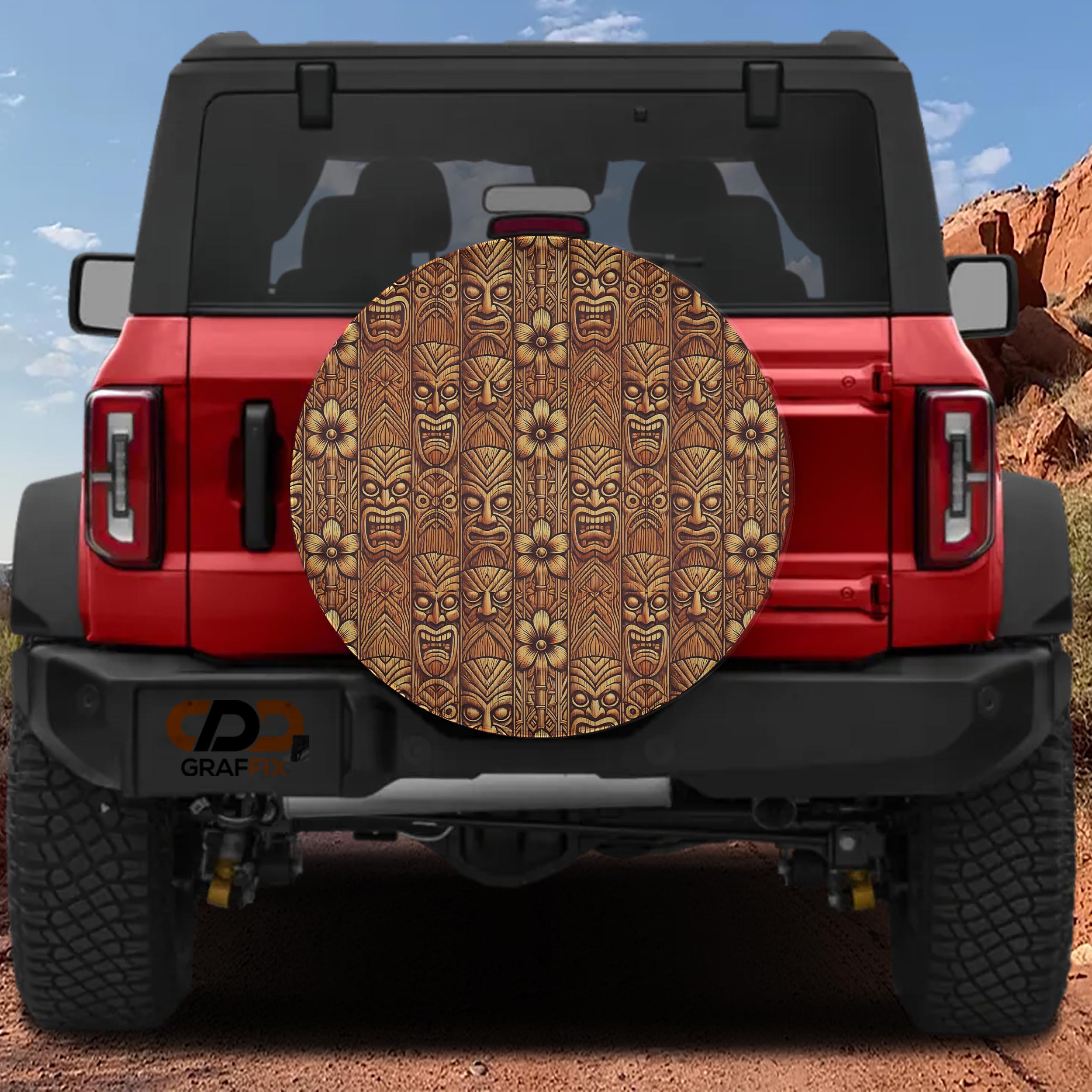 Polynesian Tiki Wood carved totem pattern spare tire cover mounted on red Ford Bronco at desert site
