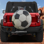 Soccer ball spare tire cover rear angle view on parked Jeep with backup camera cutout