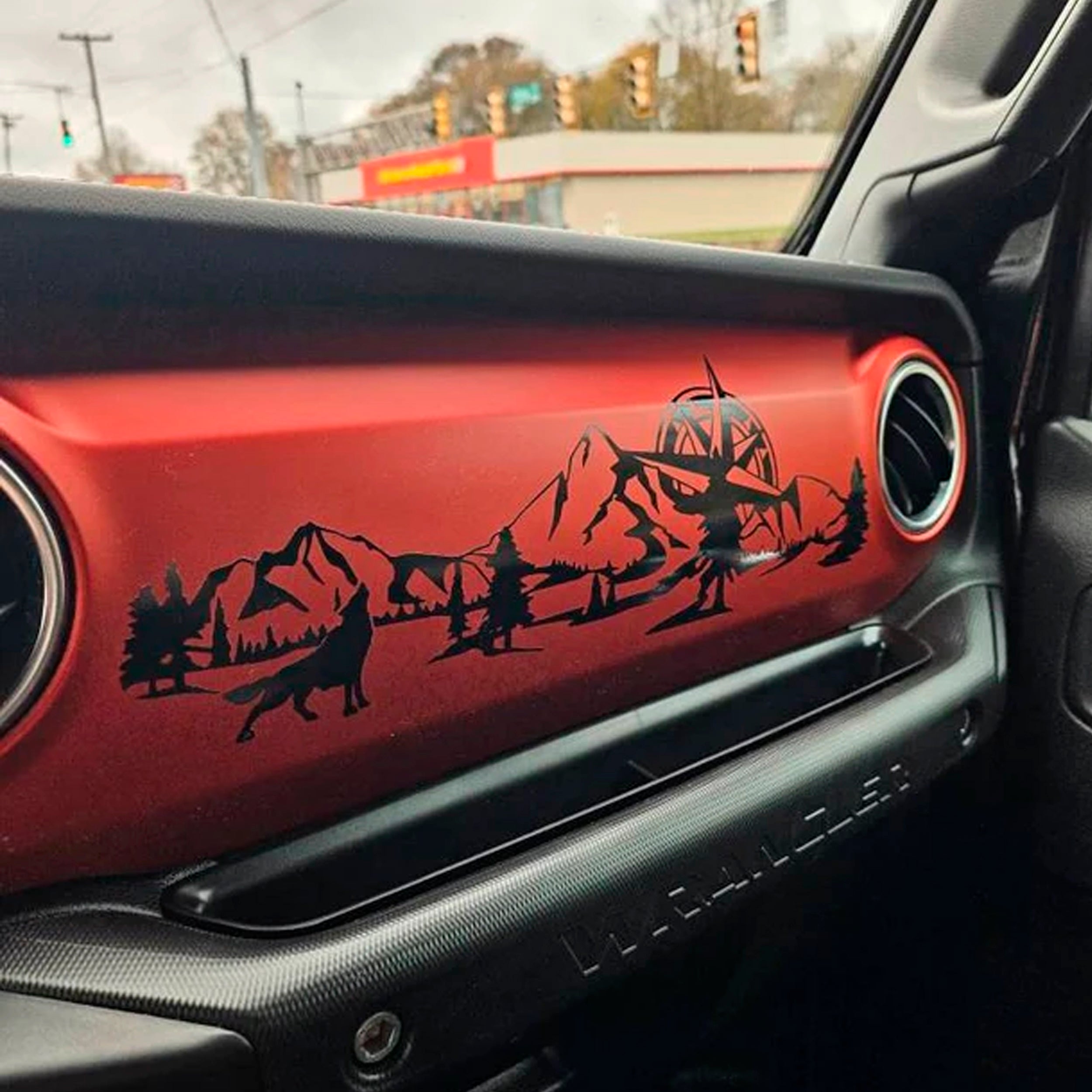 Real photo of wolf mountain compass dashboard decal applied to red Jeep Wrangler JL interior trim