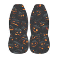 a pair of black shoes with a repeating pattern of orange and black jack-o'-lantern faces on the soles.