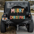 a black Jeep Wrangler with a large, colorful tire cover that says "MERRY CHRISTMAS" in a festive font.