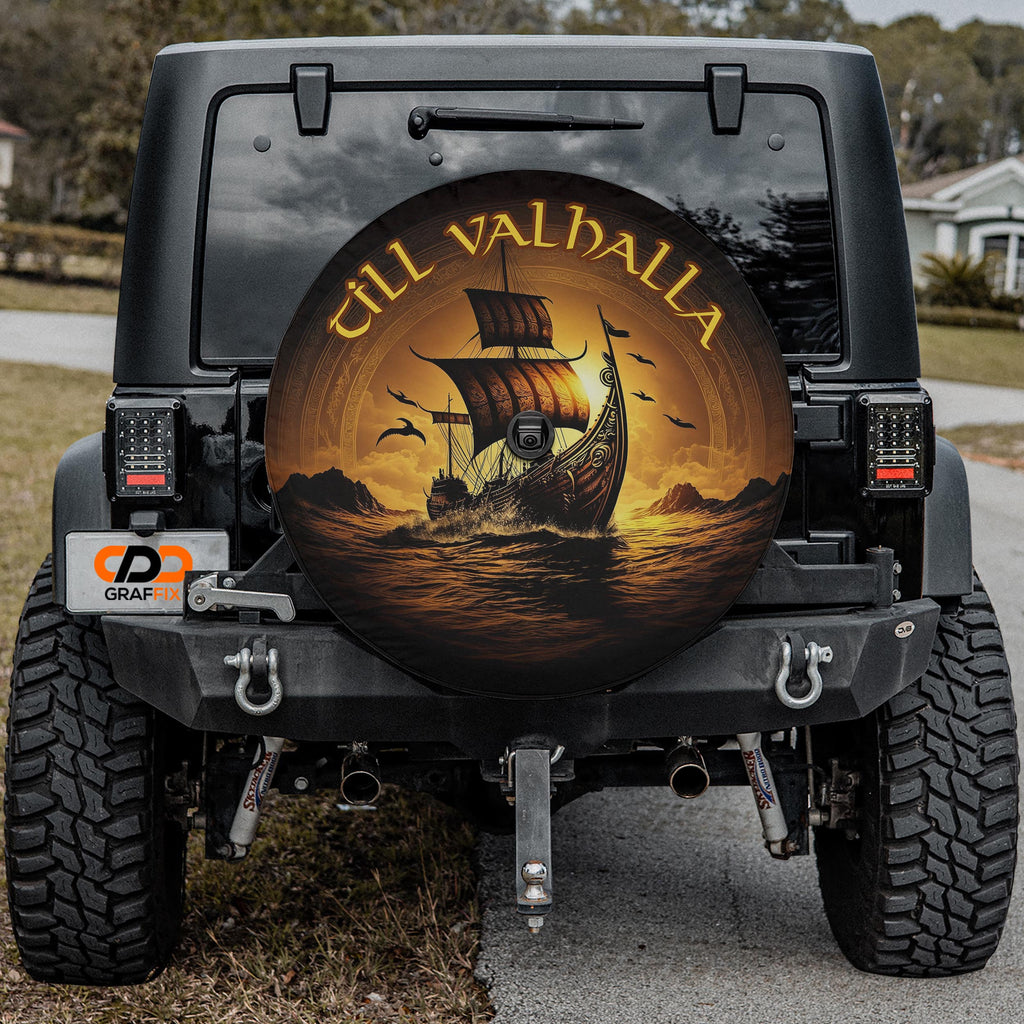 a black jeep with a large, round spare tire cover on the rear. The cover has a design of a ship sailing on the ocean, with the words "Till Valhall" written on it.