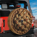 A large pie wheel cover is attached to the rear of a red Jeep, with a desert landscape visible in the background.
