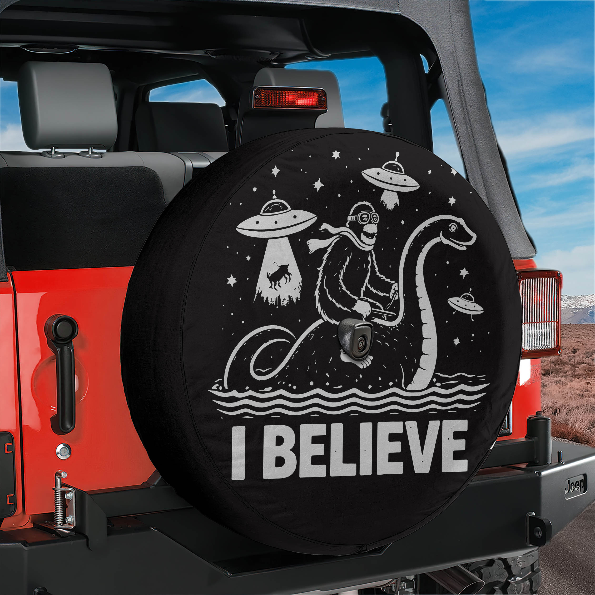 A black tire cover with a cartoon image of a person riding a giant sea creature and the text "I BELIEVE" printed on it.