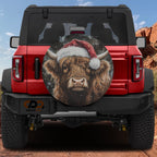 Highland Christmas Cow spare tire cover on a red Jeep Wrangler with shaggy cow in a Santa hat