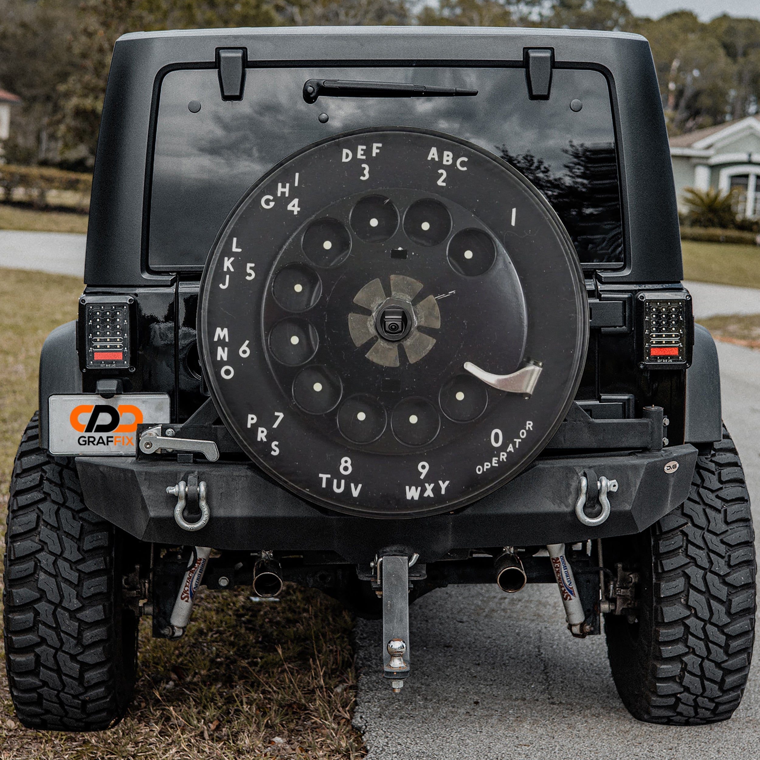 Vintage rotary phone dial spare tire cover on red Bronco rear with classic black dial graphic