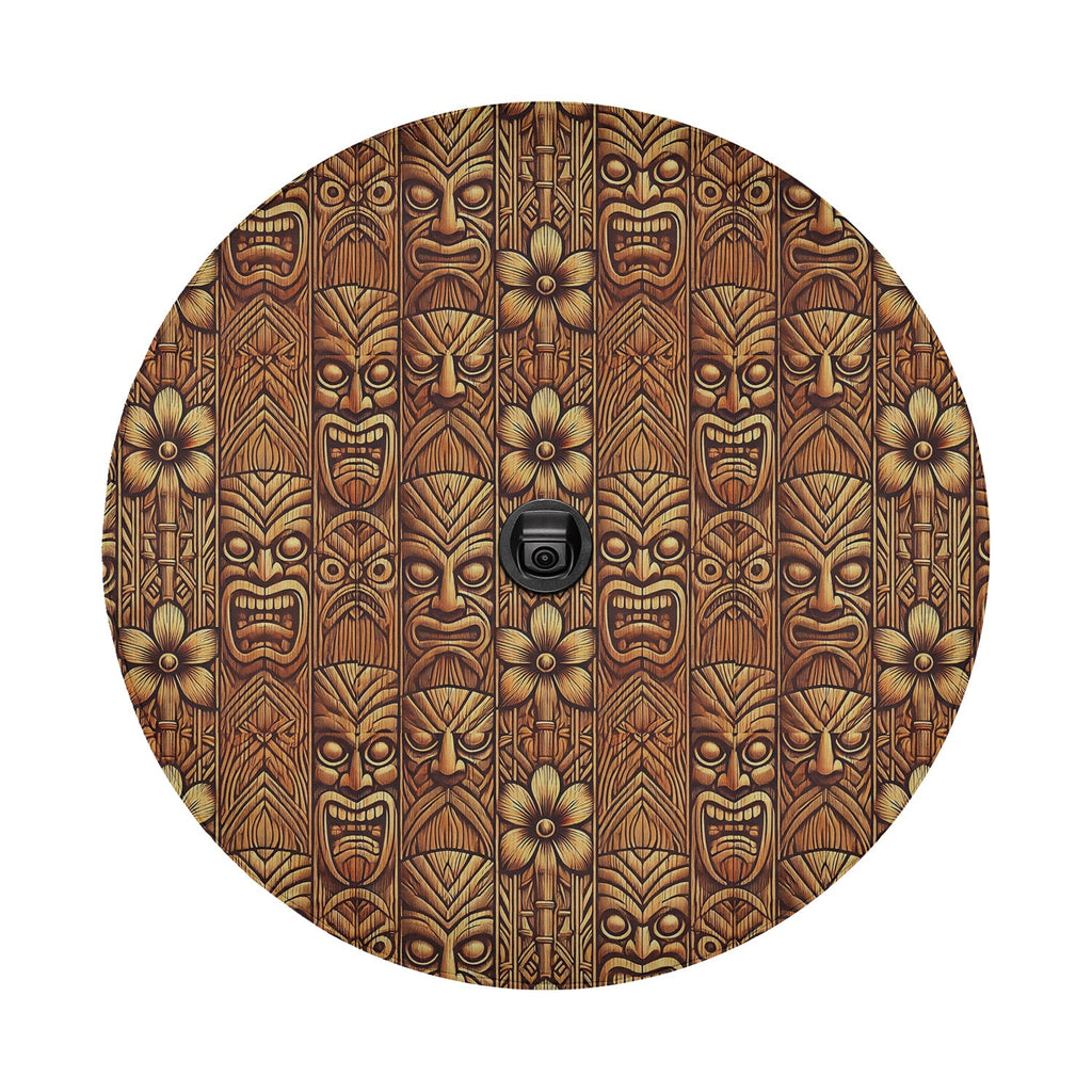 Tiki wood mask spare tire cover with carved Polynesian tiki faces and tropical flowers in warm brown tones