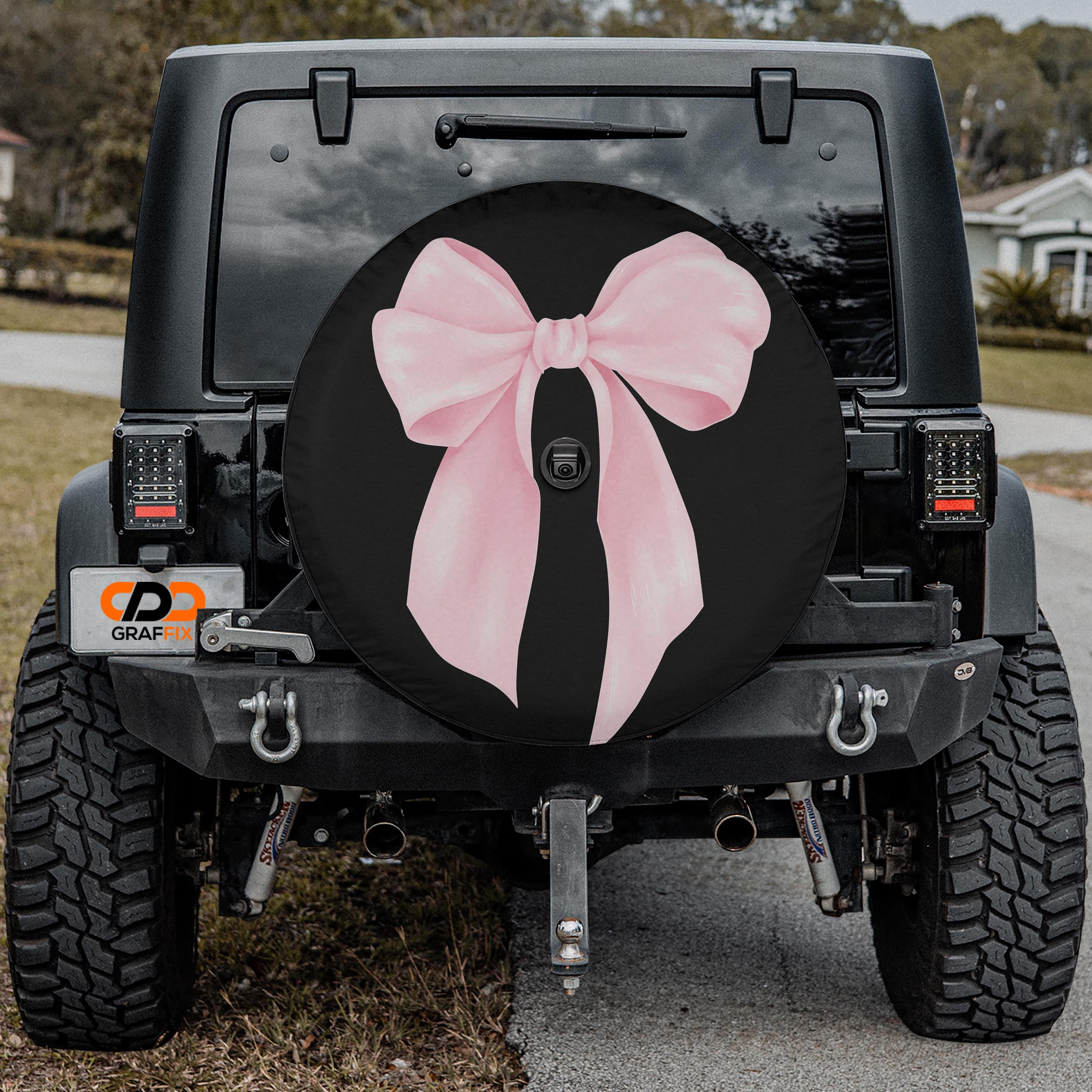 the rear of a black Jeep Wrangler with a large pink bow on the spare tire cover.