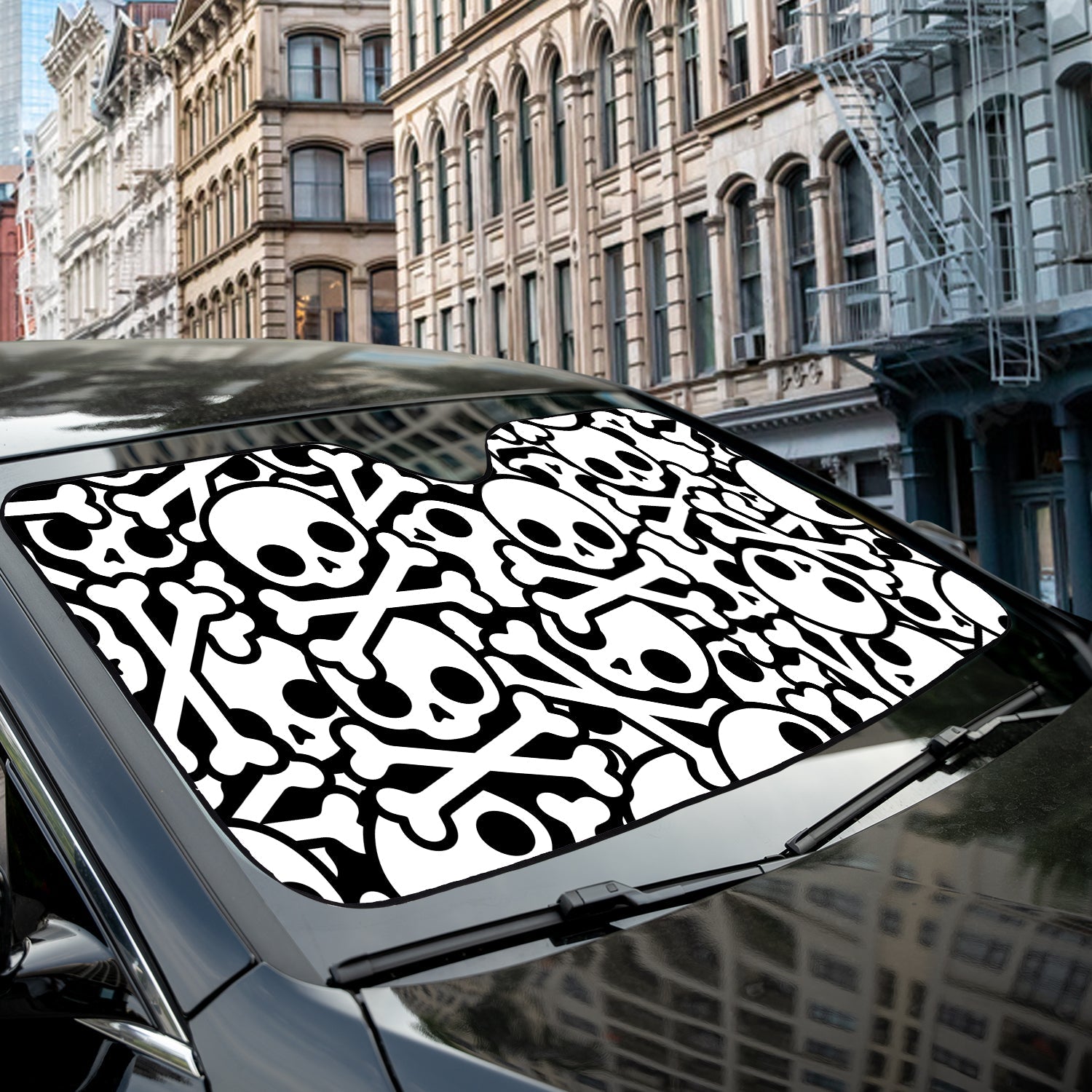 Skull and Crossbones accordion sunshade close-up installed on a dark sedan windshield exterior detail