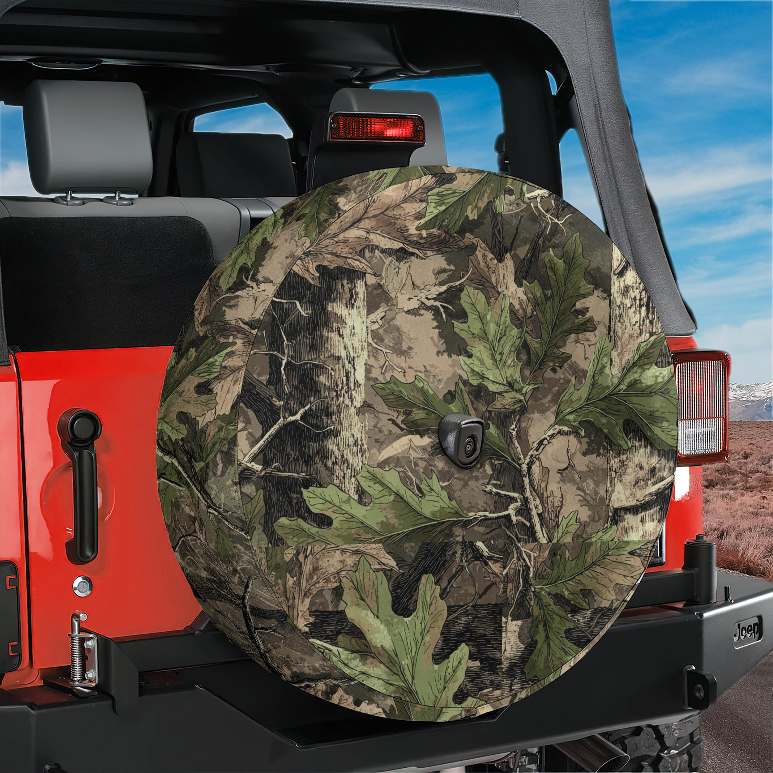 A camouflage-patterned spare tire is attached to the rear of a red Jeep, with a clear blue sky and mountains visible in the background.