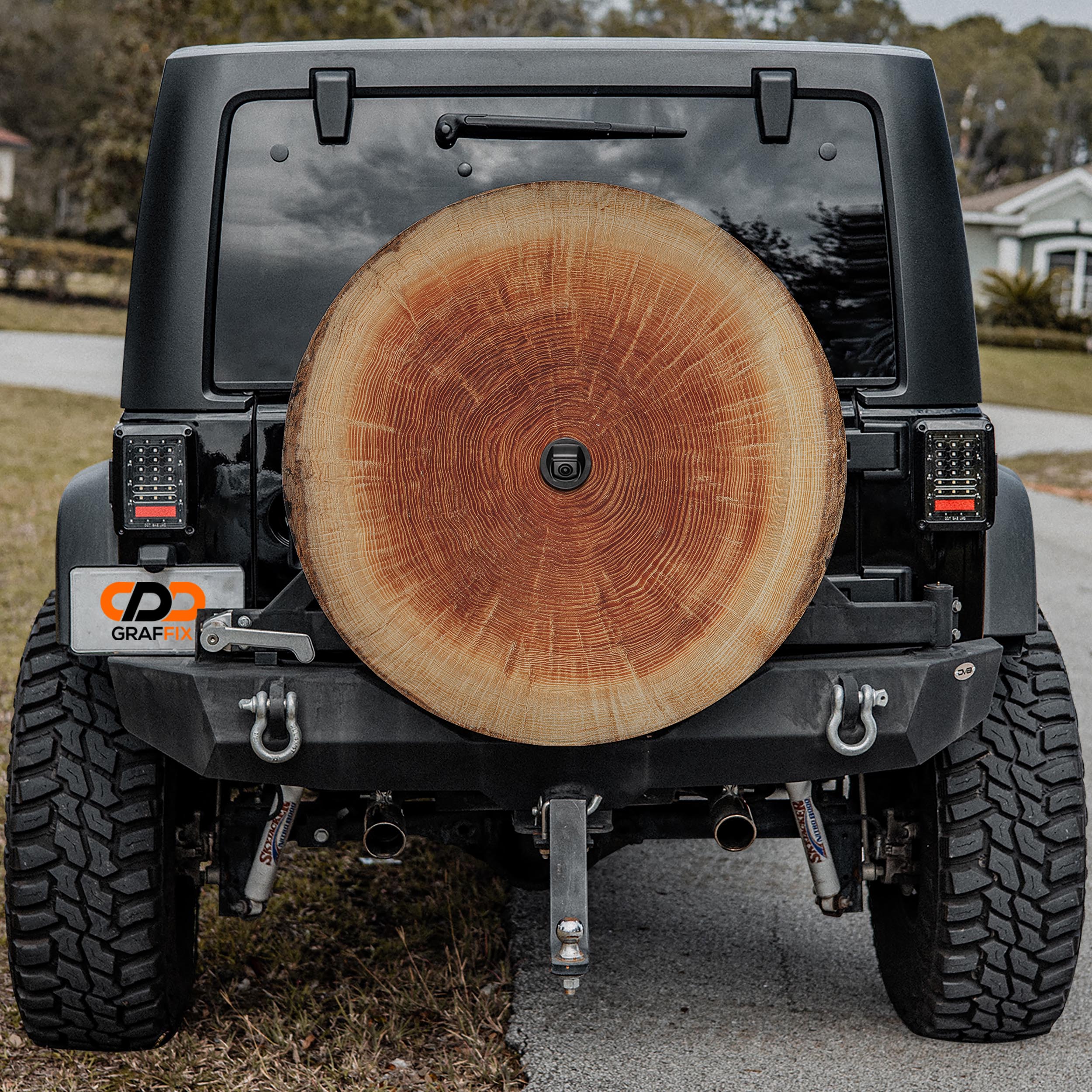 a black Jeep Wrangler with a large tree trunk mounted on the rear of the vehicle.