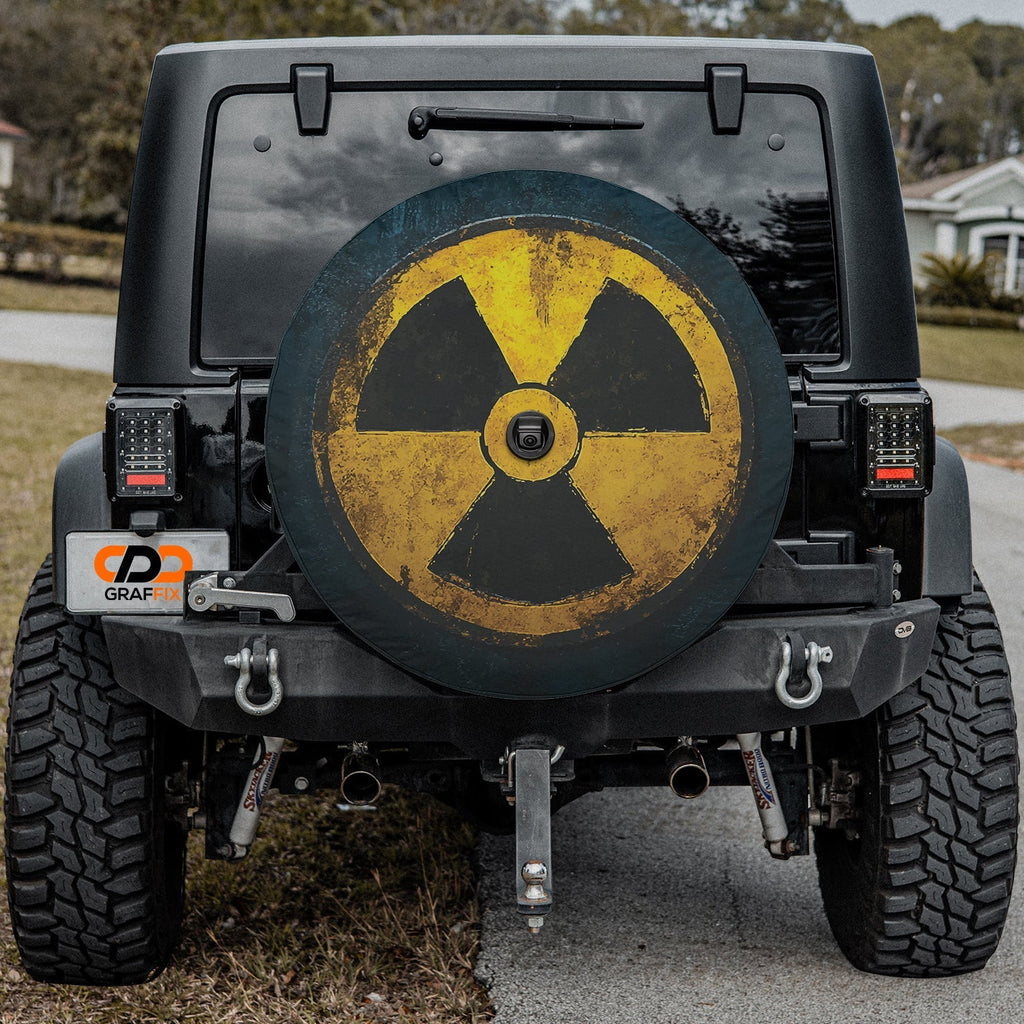 Close-up fallout shelter radiation spare tire cover disc with weathered yellow trefoil and camera hole opening