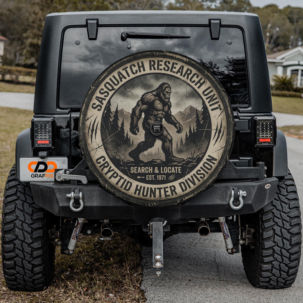 a black Jeep with a large tire cover on the back, displaying a Sasquatch logo and text related to the Sasquatch Research Unit.
