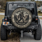 a black Jeep with a large tire cover on the back, displaying a Sasquatch logo and text related to the Sasquatch Research Unit.