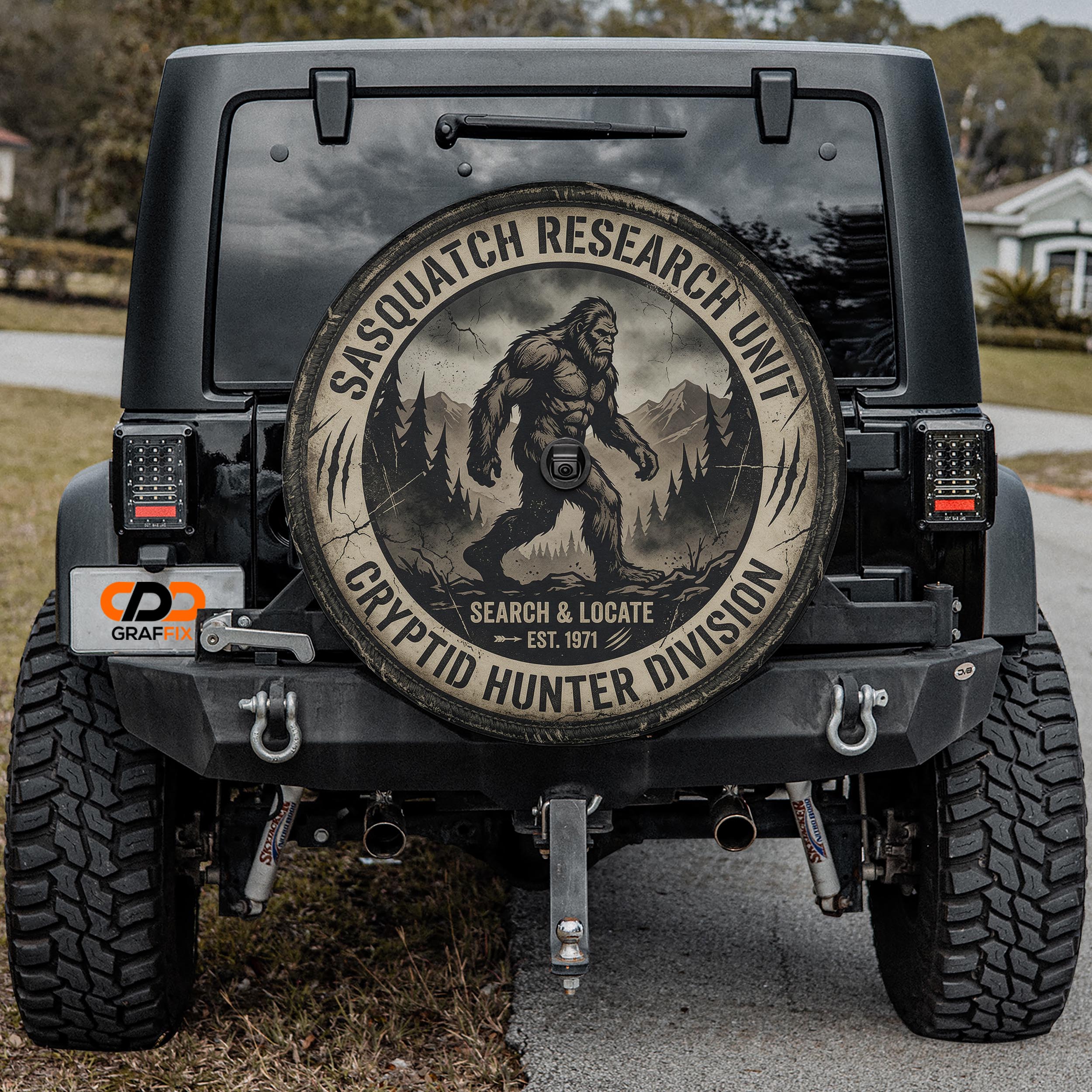 a black Jeep with a large tire cover on the back, displaying a Sasquatch logo and text related to the Sasquatch Research Unit.