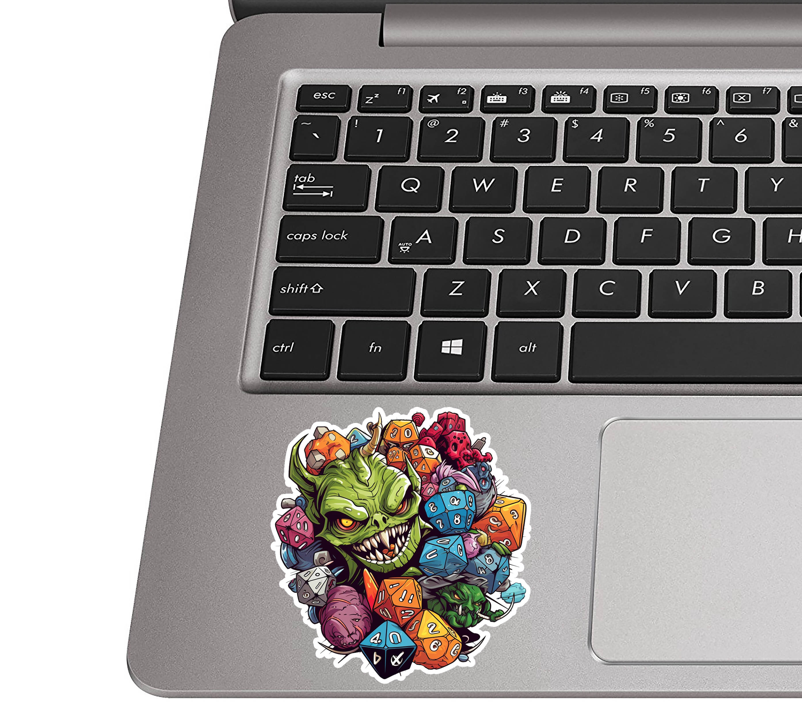 Goblin and D&D dice sticker applied to a silver laptop palm rest beside a QWERTY keyboard for scale view