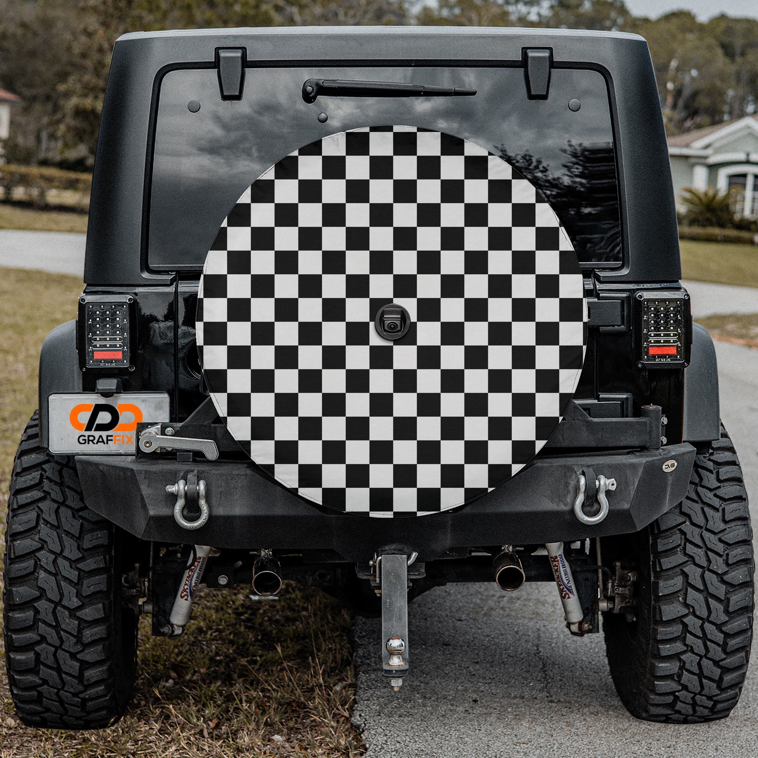 Black and white checkered board spare tire cover on black Jeep Wrangler with CDD GRAFFIX badge