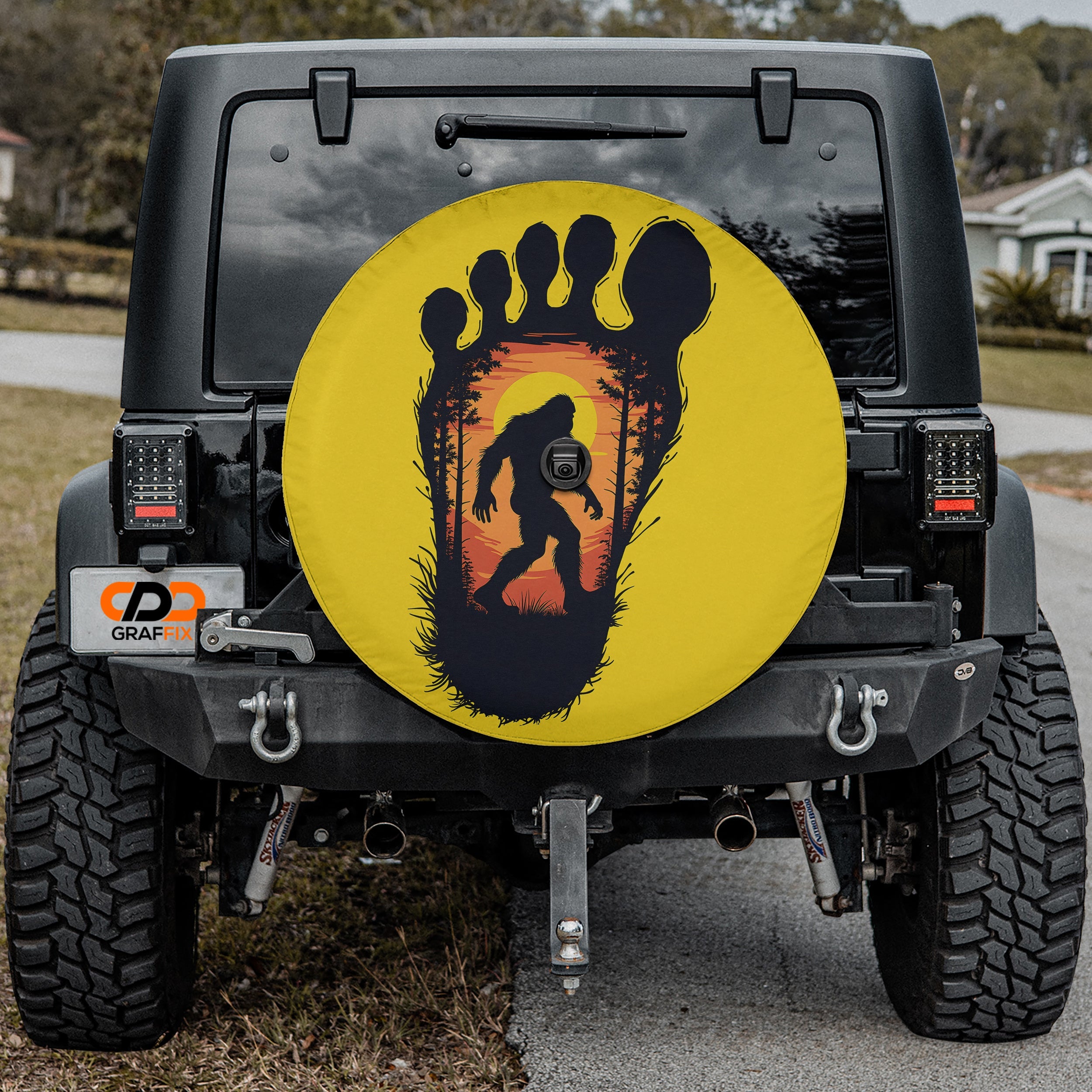 Squatch Track spare tire cover on red Jeep Wrangler featuring Bigfoot inside footprint graphic