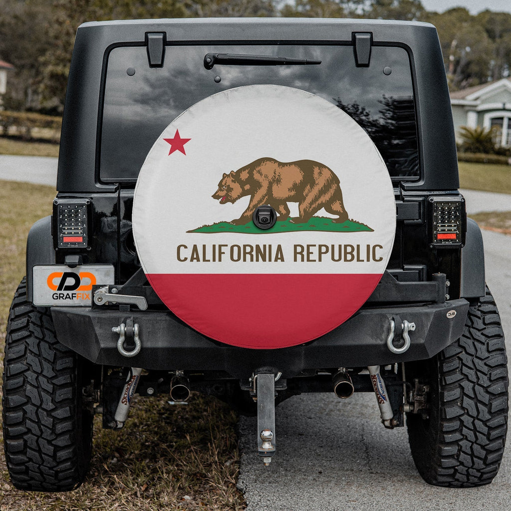 California Republic state flag spare tire cover on red Jeep Wrangler with desert backdrop featuring grizzly bear