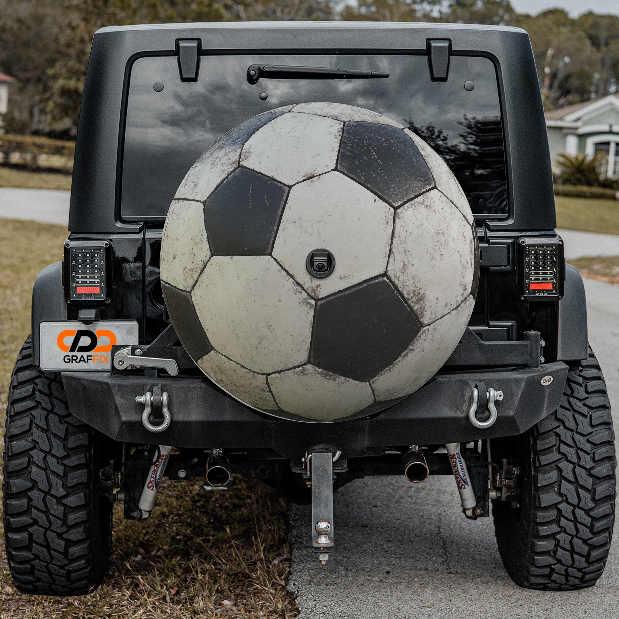 Soccer ball black and white spare tire cover mounted on black Jeep Wrangler rear outdoors