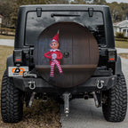 Shelfside Shenanigans spare tire cover mounted on a Jeep rear wheel displaying the festive shelf elf illustration