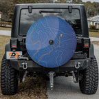 Close-up topographic trails spare tire cover disc with blue contour map, trail markers and backup camera hole
