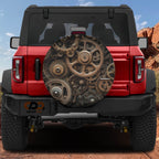 Bronze steampunk gears and sprockets spare tire cover mounted on red Ford Bronco in red rock desert